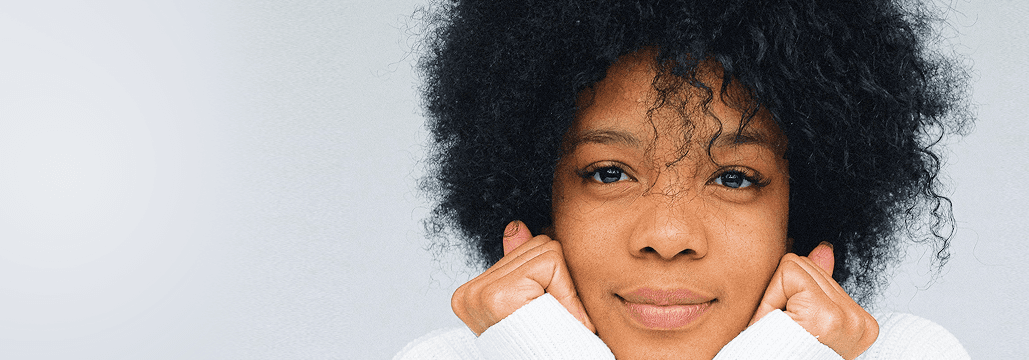 Young Black person with curly hair smiling gently