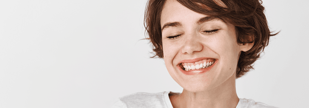 Young woman with short dark hair smiling with eyes closed